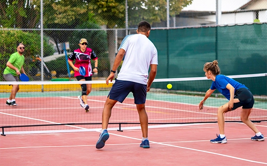 Pickleball game played on small court with paddle and perforated ball